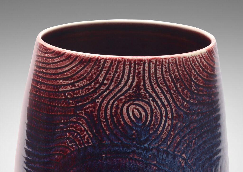 Gallery BAC Gallery BAC ovoid form with wide mouth and carved organic coiling and radiating linear pattern, glazed in oxblood with hints of purple and pale gray