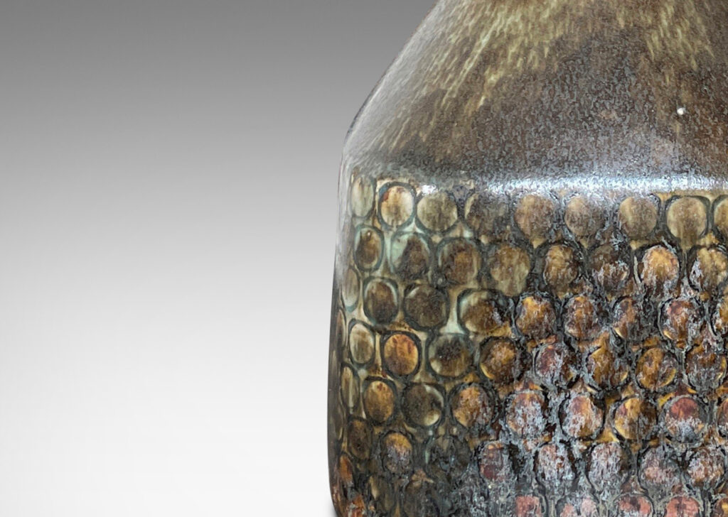 Gallery BAC square bottle-like form with rows of carved circle motifs and sprouting neck, glazed in a greenish-gray tone