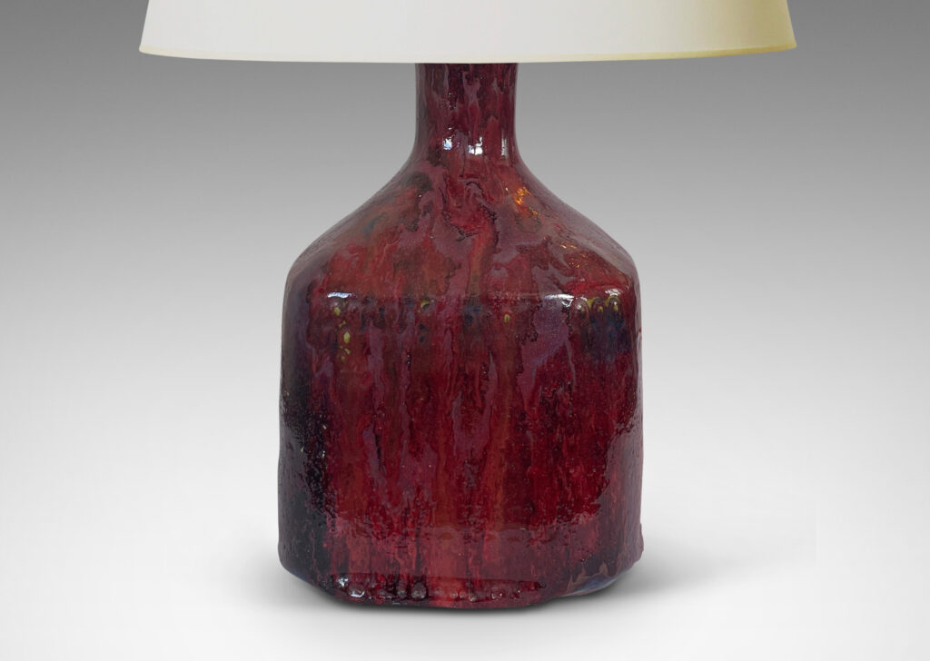 Gallery BAC square bottle-like form with rows of carved circle motifs and sprouting neck, glazed in a thick flowing burgundy-oxblood tone