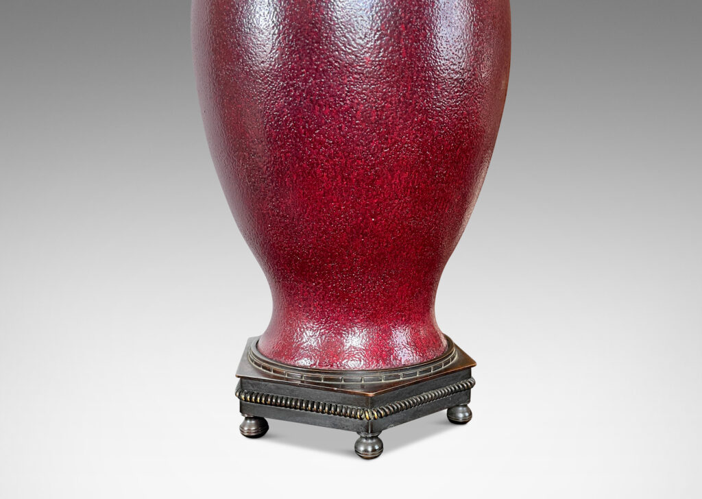 Gallery BAC elegant vase form glazed in a rich oxblood glaze with a subtle orange peel finish, mounted on an octagonal base