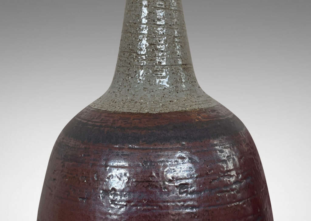 Gallery BAC bulbous forms with tall, conical necks, glazed in pale gray with burgundy luster