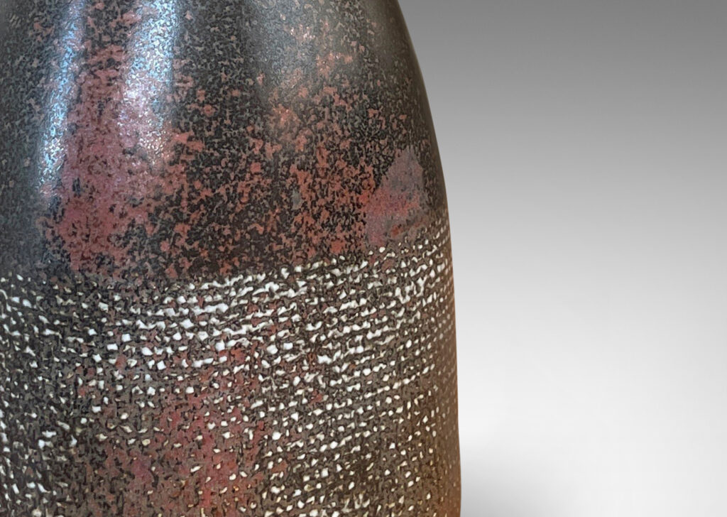 Gallery BAC bottle-like form with conical neck and textured body, glazed in black with red luster and pale gray aspects