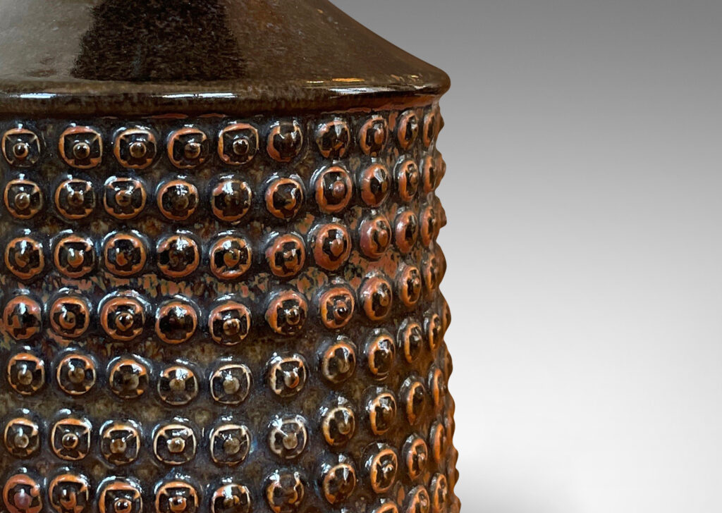 Gallery BAC knobbed drum form with spouting neck, glazed in black with rust accents