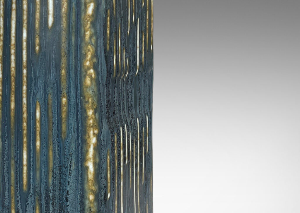 Gallery BAC cove-sided bottle forms glazed in a deep blue with gray-brown mottling