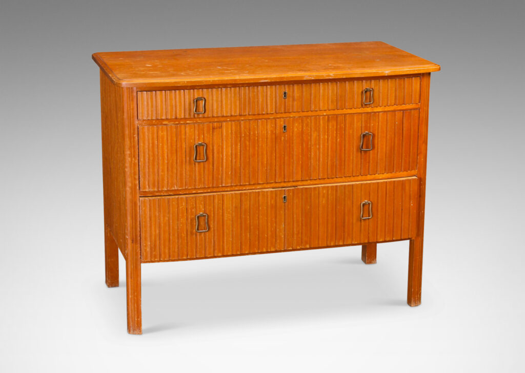 Gallery BAC three drawers with relief vertical ridges covering sides and legs, and organically modeled pulls; mahogany and brass