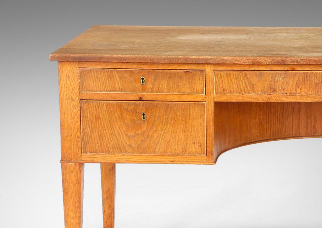 Gallery BAC beveled top edge, five drawers, tapered legs and arced knee well; oak