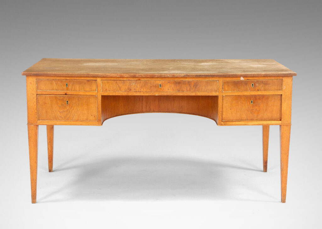 Gallery BAC beveled top edge, five drawers, tapered legs and arced knee well; oak