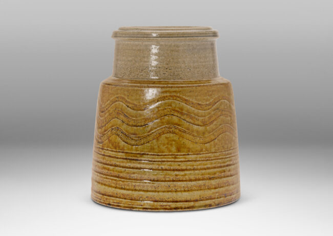 Gallery BAC raked cylindrica form with inset neck and carved wave pattern and grooves, glazed in golden honey and pale gray tones