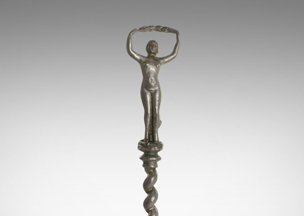 Gallery BAC polished disk with handle in the form of a barley twist with a female figure; pewter and white metal;