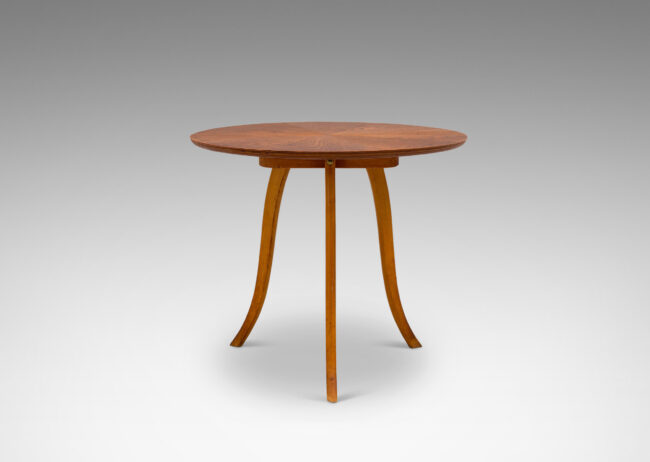 Gallery BAC floating round top with sunburst grain, perched on three sinuously modeled legs; elm