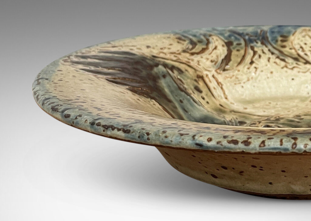 Gallery BAC wide curved lip, with carved eagle design, glazed in a pale taupe-brown “Sung” glaze with blue accents