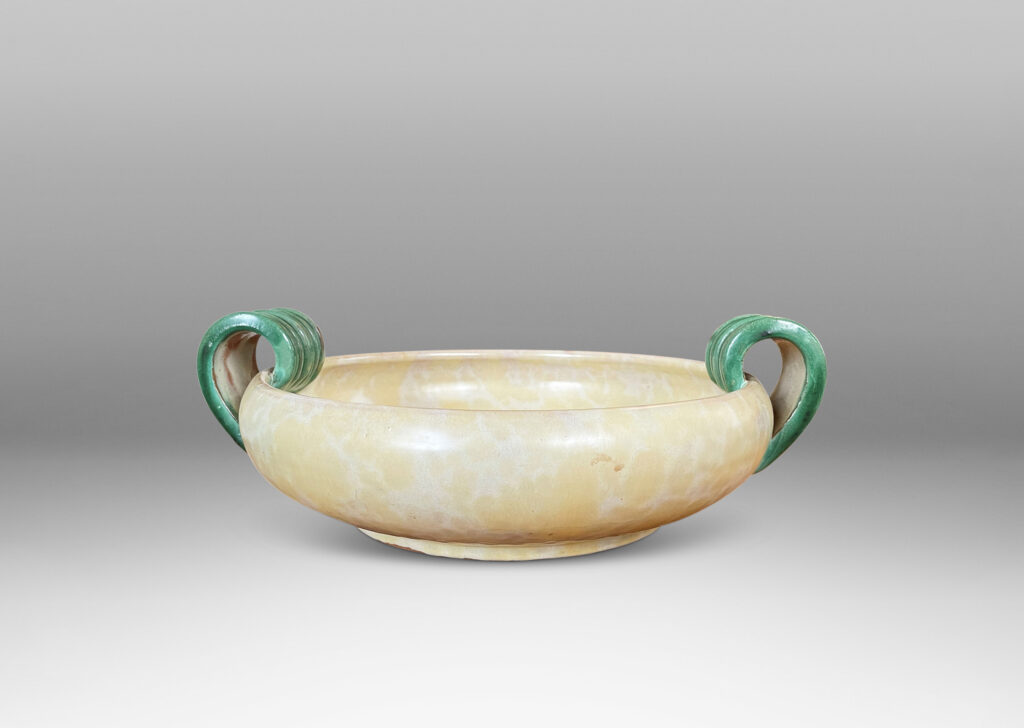 Gallery BAC softy modeled form with inward curving side and concentric ridging, glazed in a sponged pale yellow, with scroll handles in green