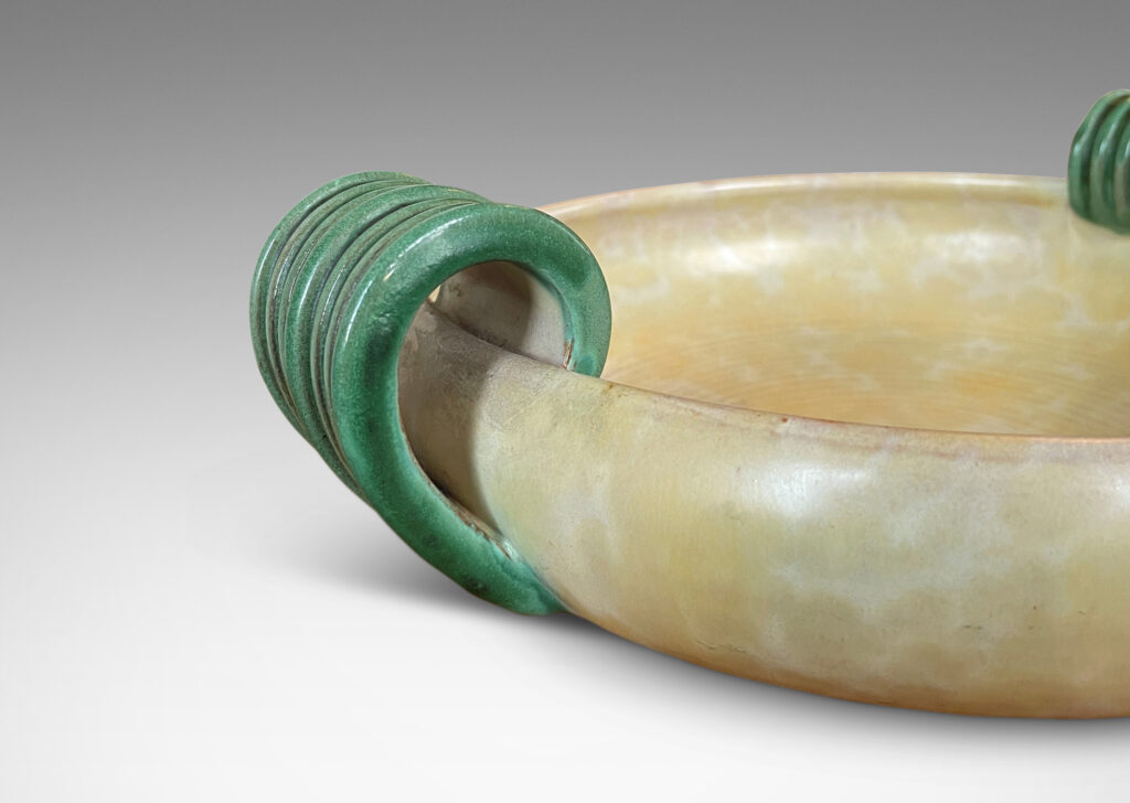 Gallery BAC softy modeled form with inward curving side and concentric ridging, glazed in a sponged pale yellow, with scroll handles in green