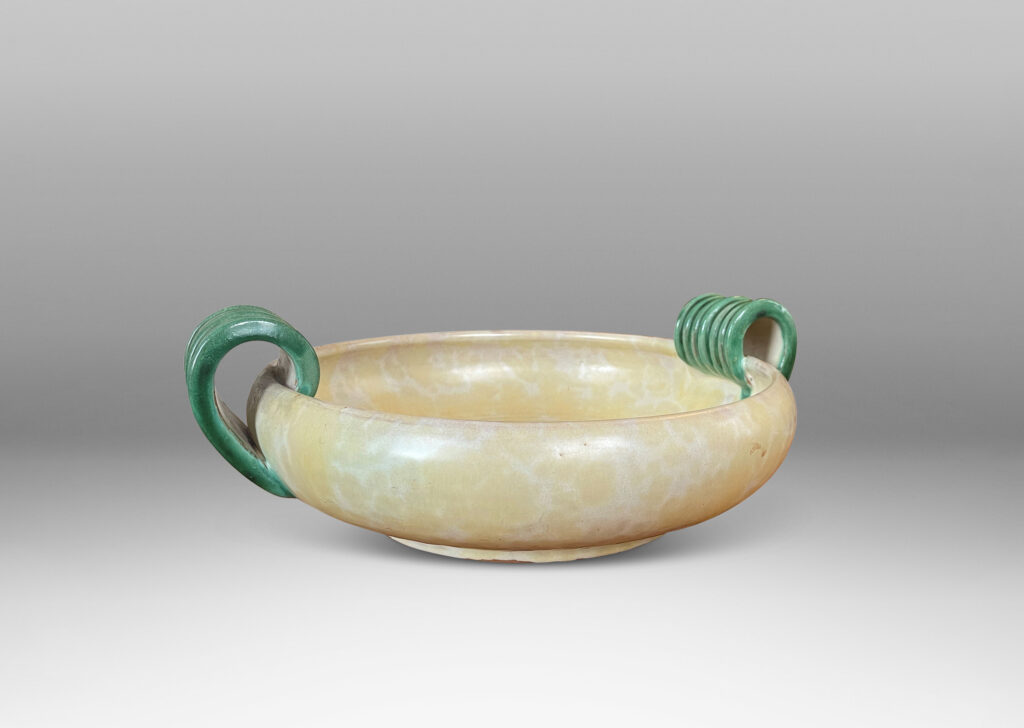 Gallery BAC softy modeled form with inward curving side and concentric ridging, glazed in a sponged pale yellow, with scroll handles in green