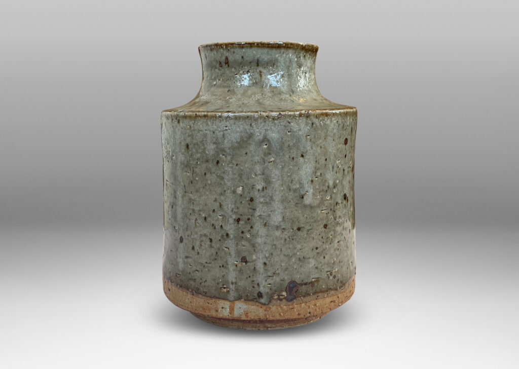 Gallery BAC cylindrical form with reveal base and coved neck with wide mouth, glazed in light green-gray with punctuated with brown speckles