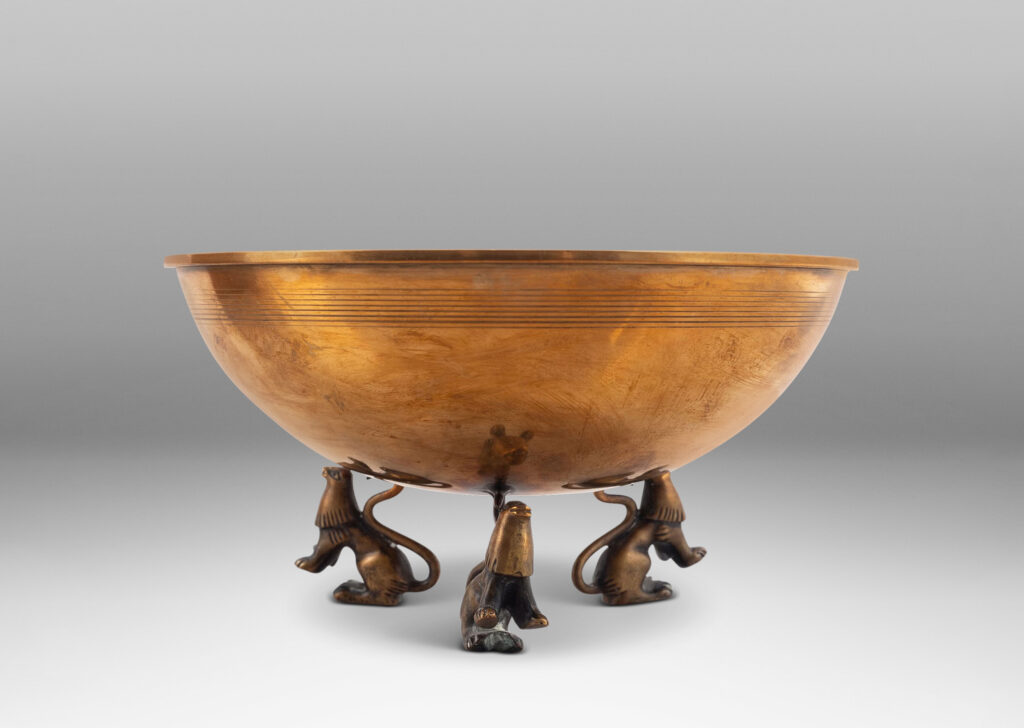 Gallery BAC hemisphere form with engraved pinstripes near rim, supported by the springing tails of three lions; bronze