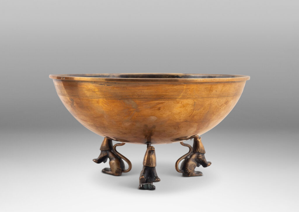 Gallery BAC hemisphere form with engraved pinstripes near rim, supported by the springing tails of three lions; bronze