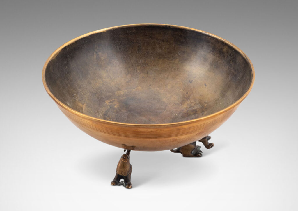 Gallery BAC hemisphere form with engraved pinstripes near rim, supported by the springing tails of three lions; bronze