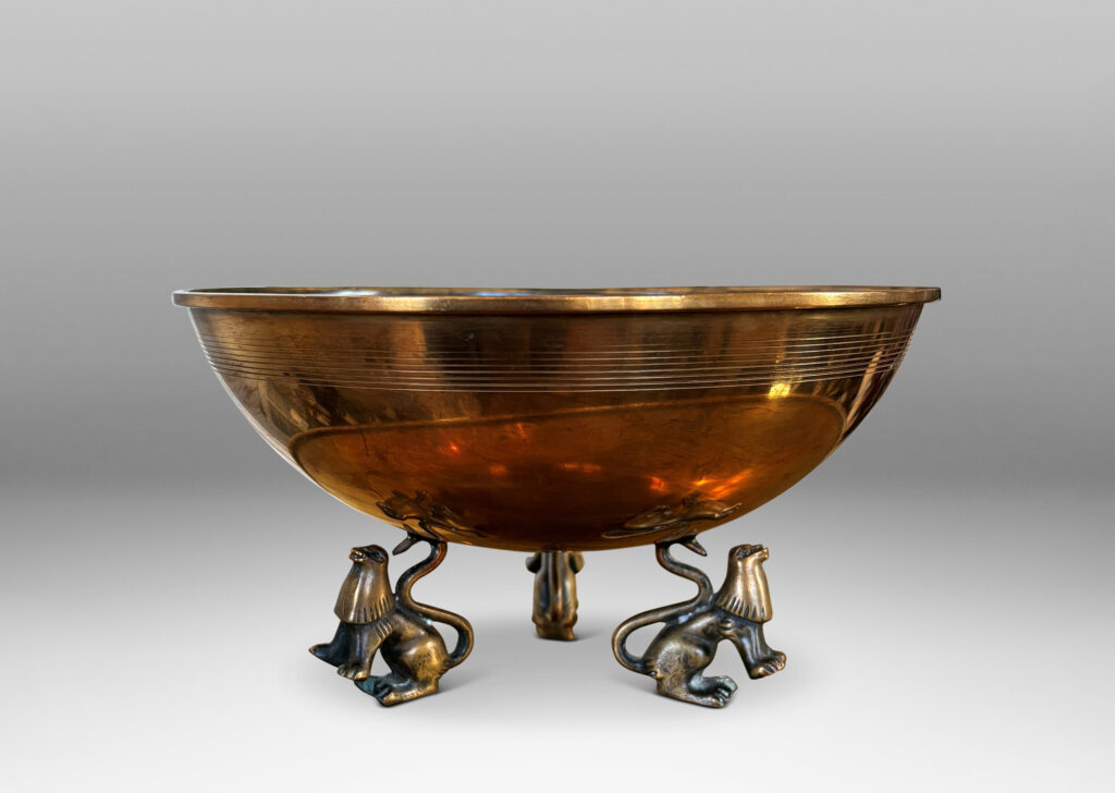 Gallery BAC hemisphere form with engraved pinstripes near rim, supported by the springing tails of three lions; bronze