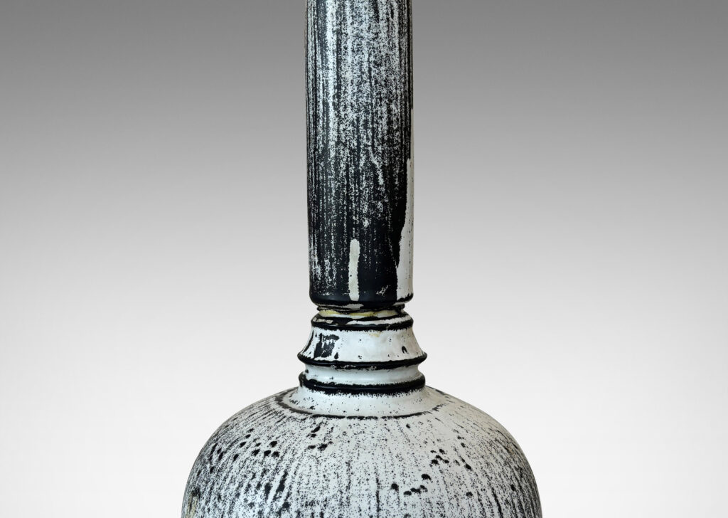 Gallery BAC wide globe form with tall neck and overall carved organic texture, in a white-black tin glaze