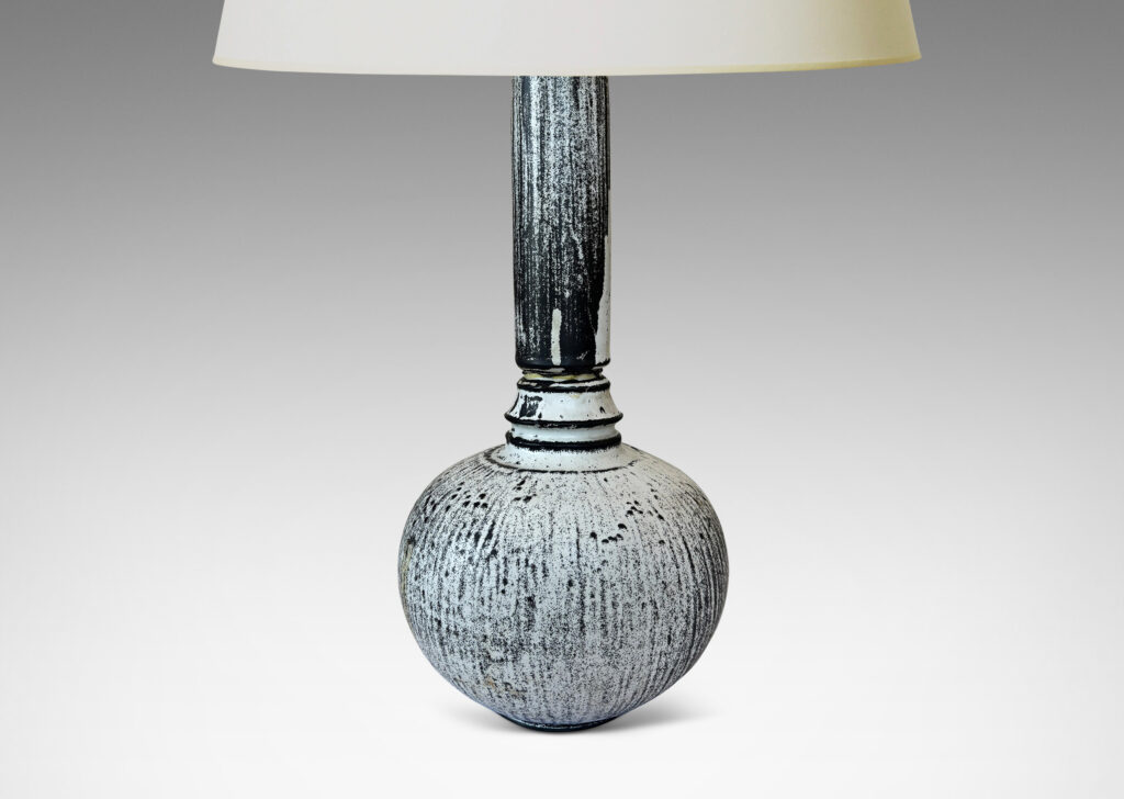 Gallery BAC wide globe form with tall neck and overall carved organic texture, in a white-black tin glaze