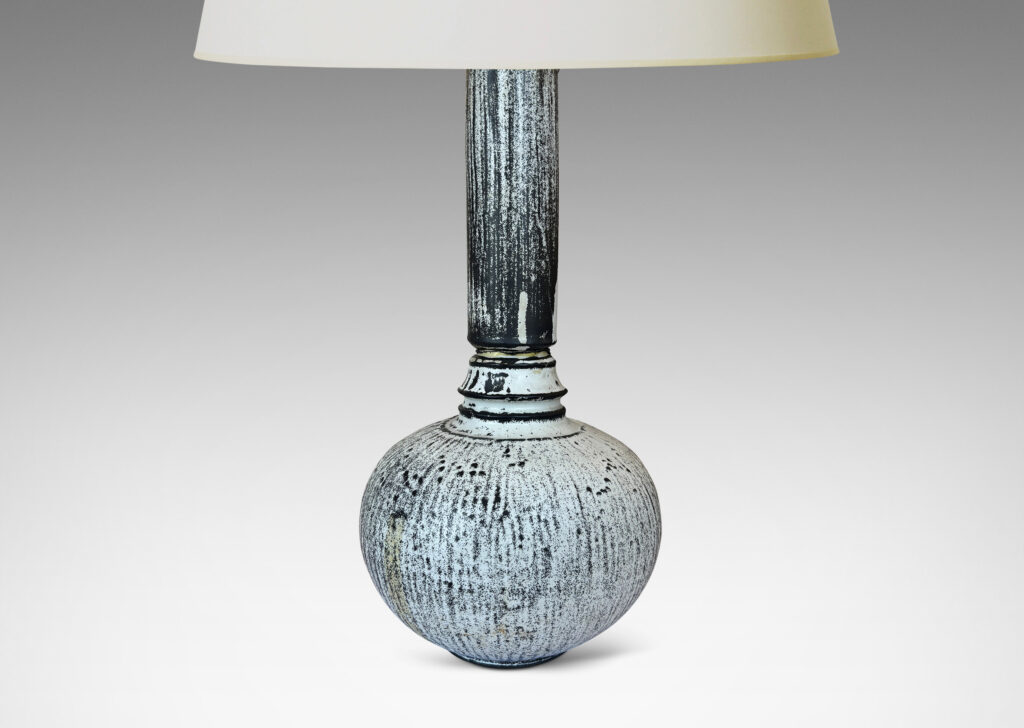 Gallery BAC wide globe form with tall neck and overall carved organic texture, in a white-black tin glaze