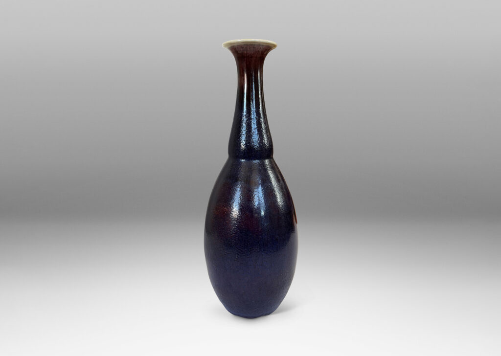 Gallery BAC ovoid body with articulated neck and flared mouth, glazed in a plummy oxblood tone with pale gray accents