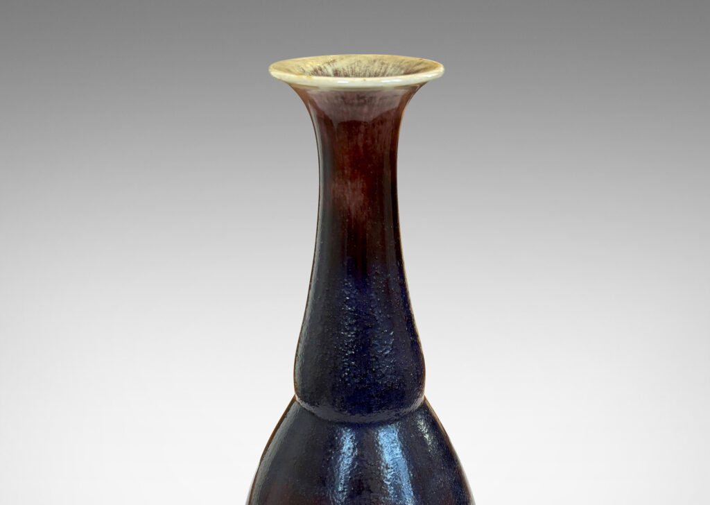 Gallery BAC ovoid body with articulated neck and flared mouth, glazed in a plummy oxblood tone with pale gray accents