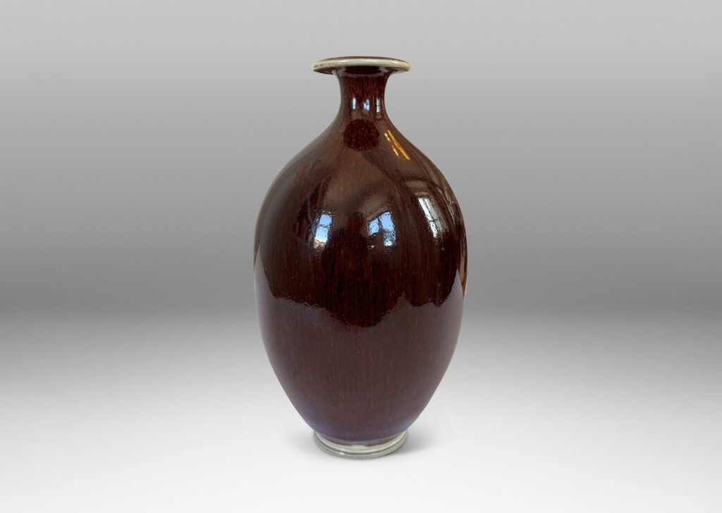Gallery BAC ovoid form with sprouting neck and flange mouth, glazed in a glossy oxblood with pale gray accents