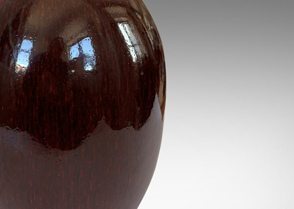 Gallery BAC ovoid form with sprouting neck and flange mouth, glazed in a glossy oxblood with pale gray accents