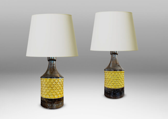Gallery BAC cylindrical forms with coved necks and geometric reliefs, glazed in a golden yellow and dark brown