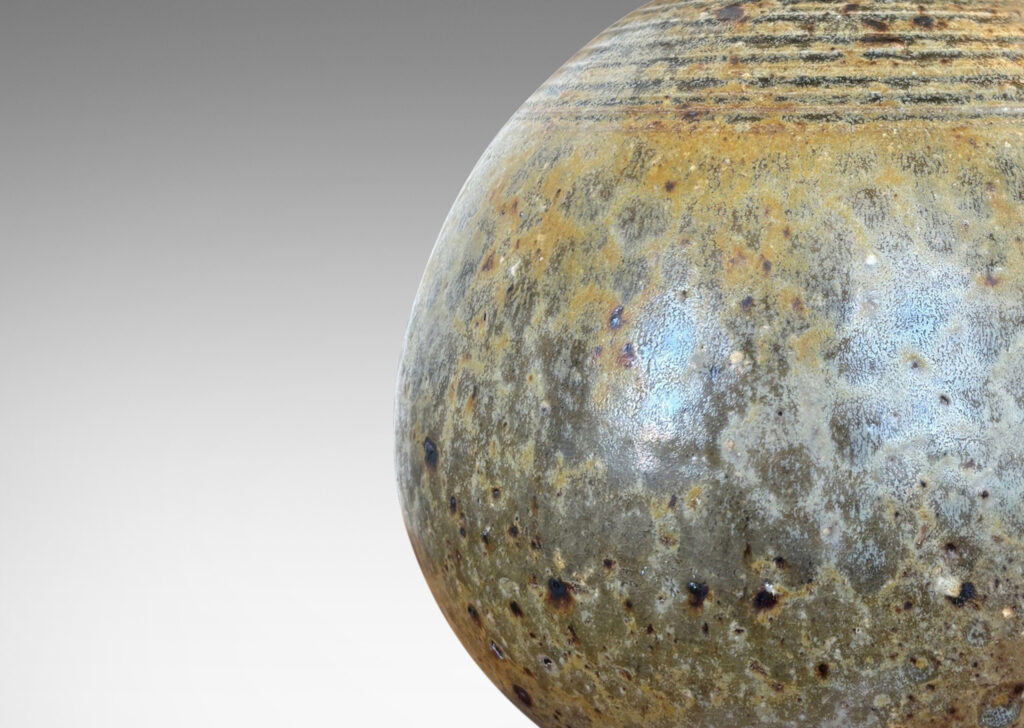 Gallery BAC blump globe form with carved rings on top and sprouting neck, glazed in pale taupe and gray