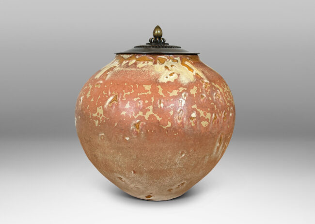 Gallery BAC apered globe form in a marvelous light tan over terra cotta glazing, with bronze patinated lid ornamented with ruffle, coil and finial