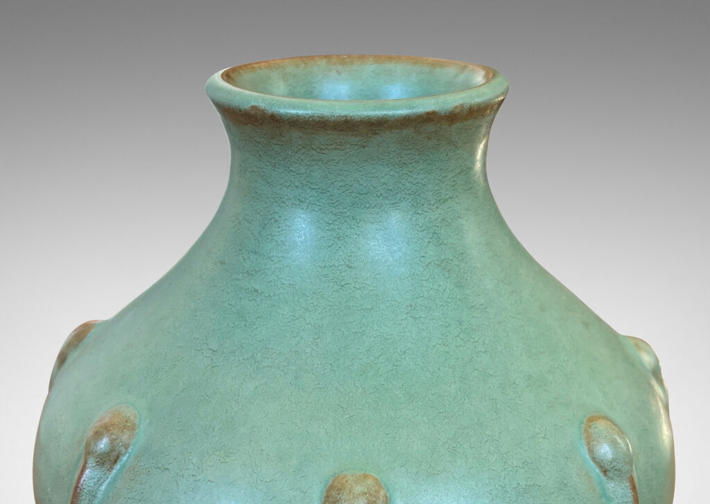Gallery BAC bulbous form with outstretched mouth and relief organic motifs, in a celadon green glaze with brown accents