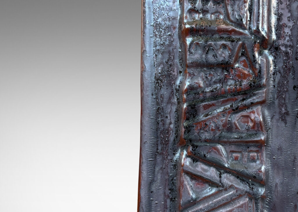 Gallery BAC rectangular bottle form with wide bands of geometric ornament in relief, glazed in an oxblood with gray glaze