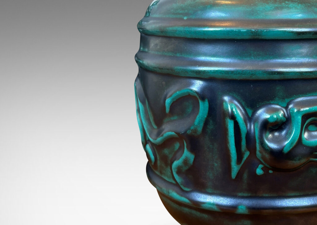 Gallery BAC wide relief band of abstract bird and foliate motifs, with lid topped with a bird finial, in deep tonal teal copper oxide glazing
