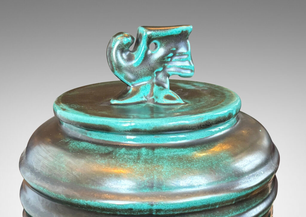 Gallery BAC wide relief band of abstract bird and foliate motifs, with lid topped with a bird finial, in deep tonal teal copper oxide glazing