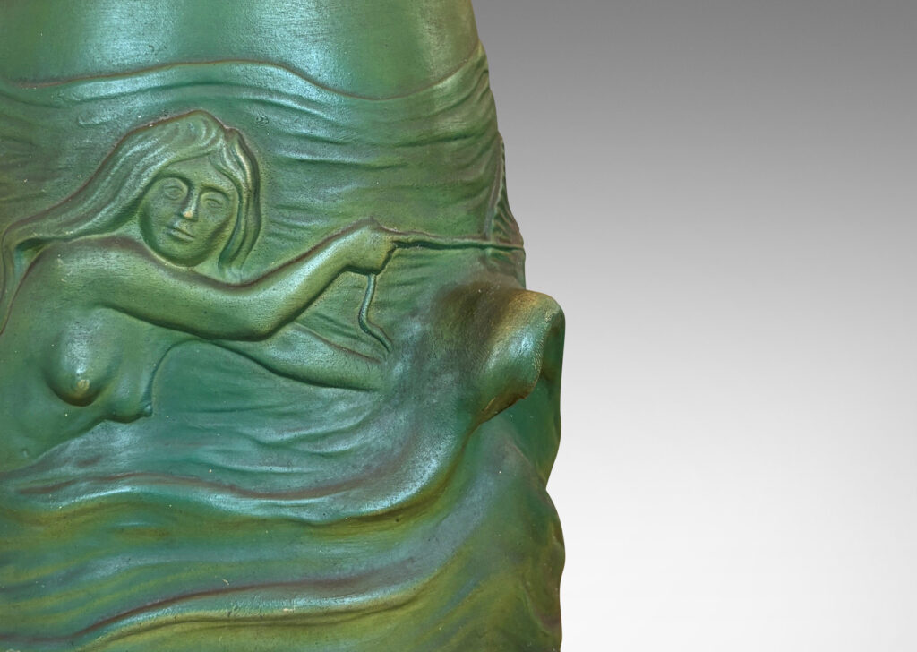 Gallery BAC bell-like form encircled in reliefs depicting waves, fish, mermaids and cloud ball motifs, glazed in a matte dark green