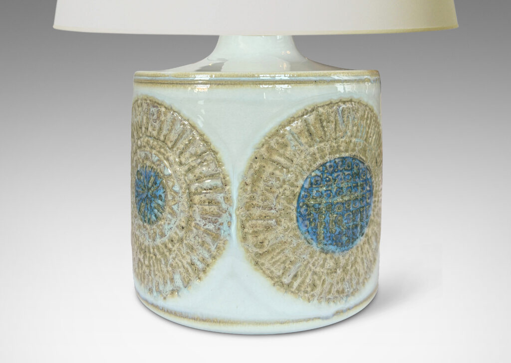 Gallery BAC drum form with relief abstracted floral motifs, glazed in olive-tan and turquoise against a pale gray background