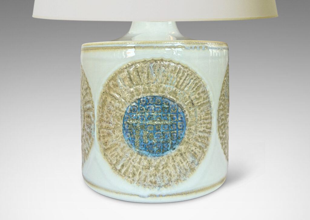 Gallery BAC drum form with relief abstracted floral motifs, glazed in olive-tan and turquoise against a pale gray background