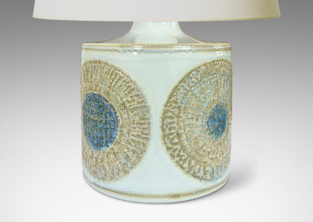 Gallery BAC drum form with relief abstracted floral motifs, glazed in olive-tan and turquoise against a pale gray background