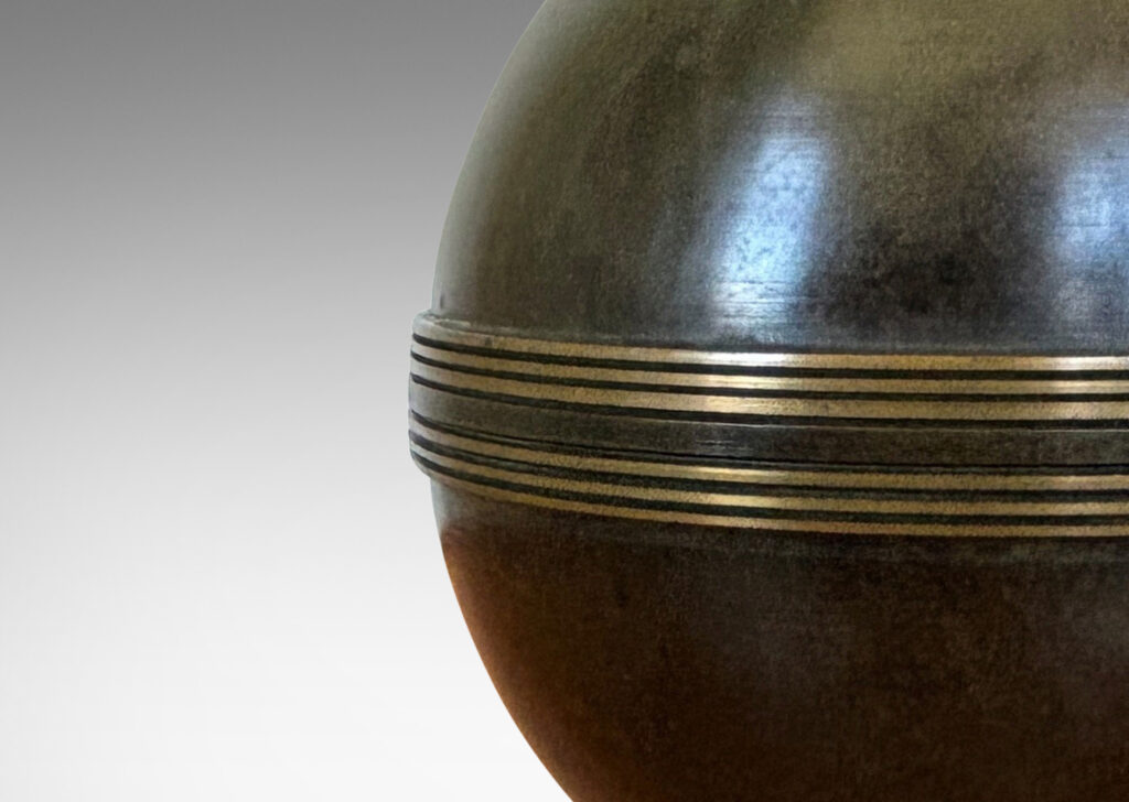 Gallery BAC globe forms with engraved bands, mounted on an angled square plinth, having a handsome original patination; bronze