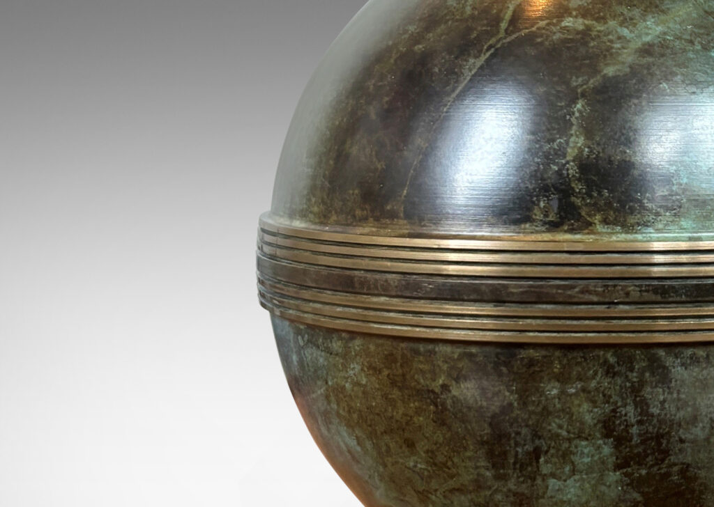 Gallery BAC globe forms with engraved bands, mounted on an angled square plinth, having a handsome original patination; bronze