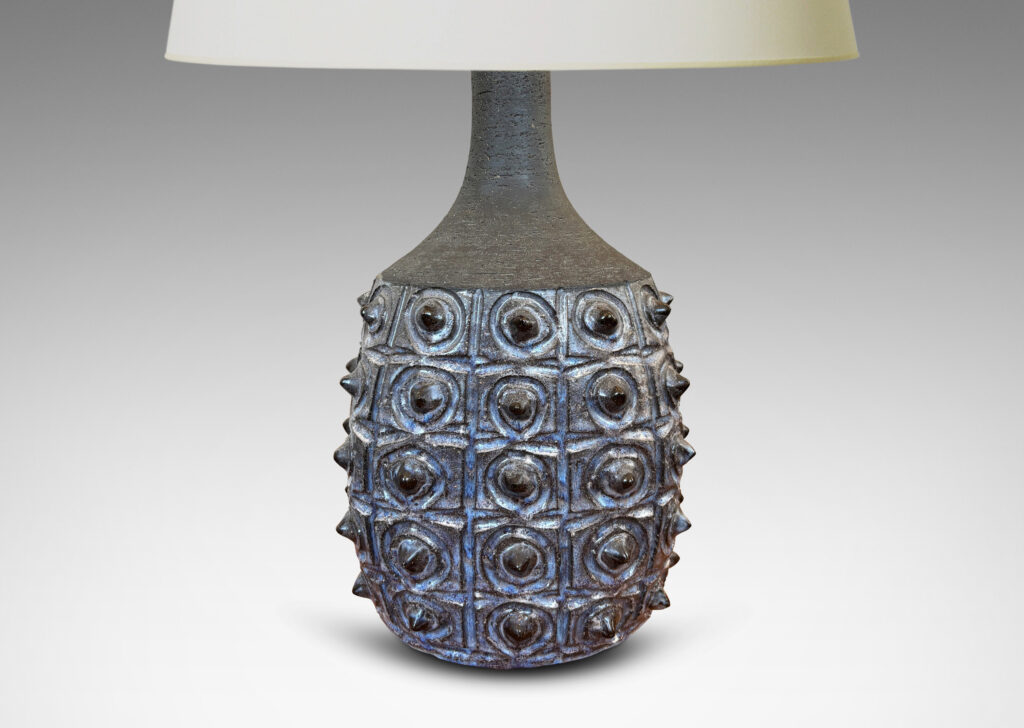 Gallery BAC swelling form with carved design and grid of projecting spines, glazed in pale and dark blue, with sprouting neck in matte brown