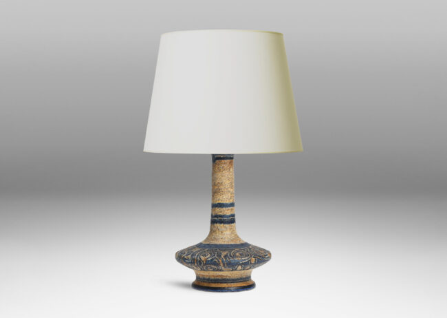 Gallery BAC decanter-like form with low wide body and tall neck, with carved swirling deign, glazed in black against dappled beige-tan