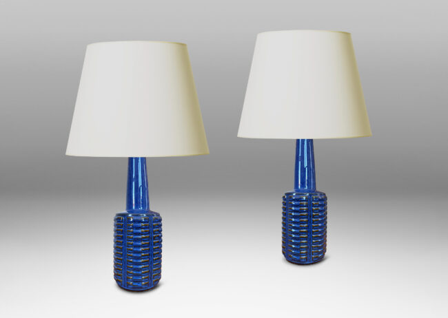 Gallery BAC cylindrical form with stacks of impressed motifs in relief and a tapered neck, glazed in a saturated blue-brown