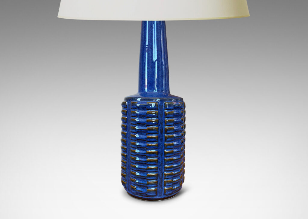 Gallery BAC cylindrical form with stacks of impressed motifs in relief and a tapered neck, glazed in a saturated blue-brown