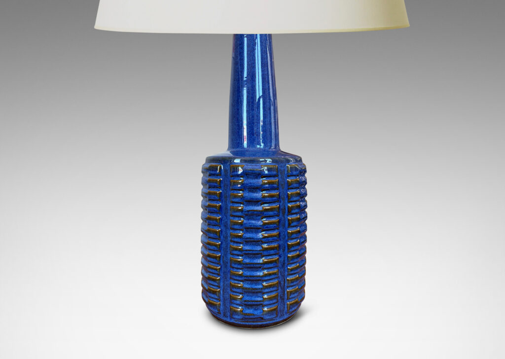 Gallery BAC cylindrical form with stacks of impressed motifs in relief and a tapered neck, glazed in a saturated blue-brown