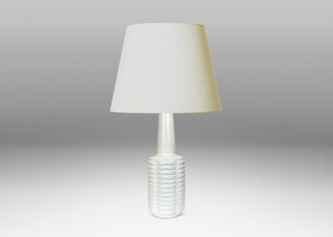 Gallery BAC cylindrical form with stacks of impressed motifs in relief and a tapered neck, glazed in a gloss white