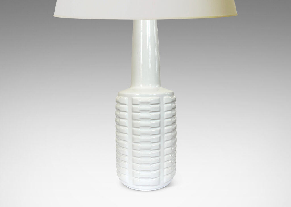 Gallery BAC cylindrical form with stacks of impressed motifs in relief and a tapered neck, glazed in a gloss white